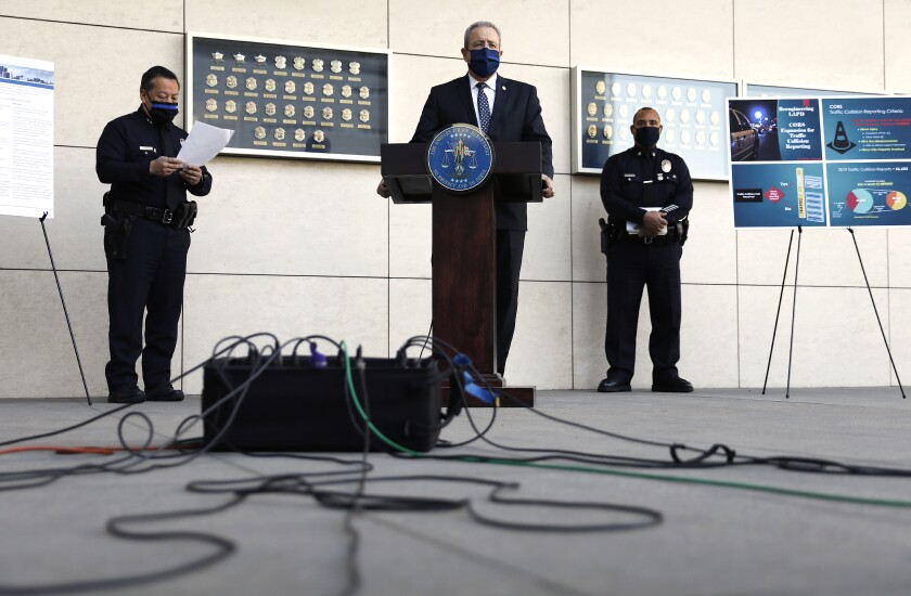 LAPD Chief Michel Moore speaks at a lectern outdoors