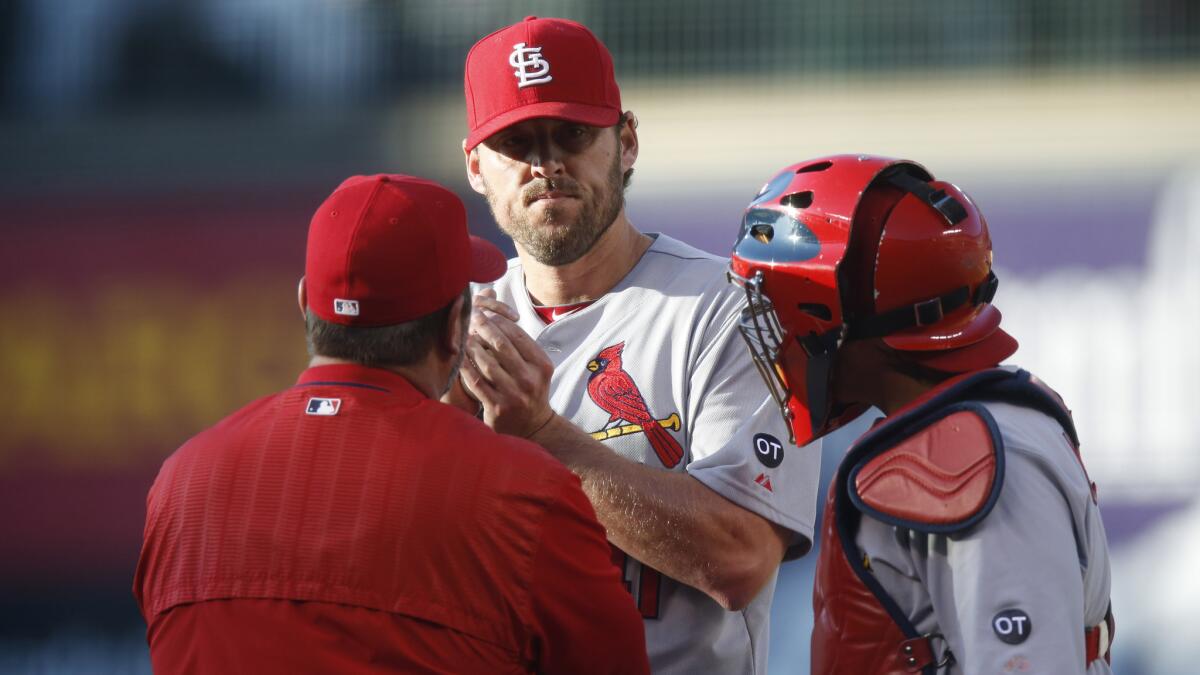 St. Louis Cardinals pitching coach Derek Lilliquist, left, speaks with pitcher John Lackey, center, and catcher Yadier Molina during a game against the Colorado Rockies on June 8.