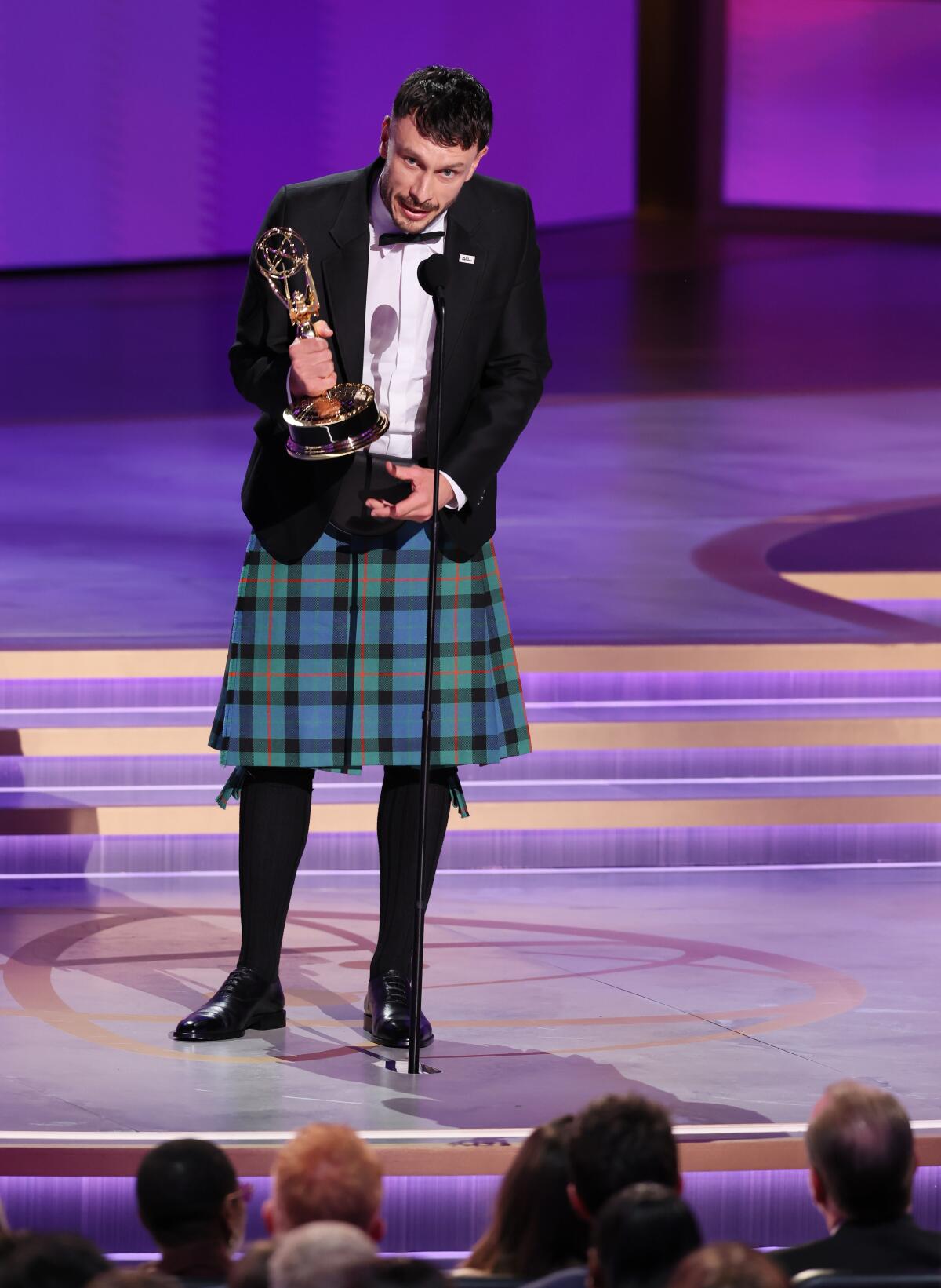 "Baby Reindeer" creator Richard Gadd stands onstage, wearing a kilt and holding an Emmy