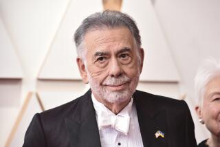 Francis Ford Coppola smiles in a black suit and white tie against a white backdrop.