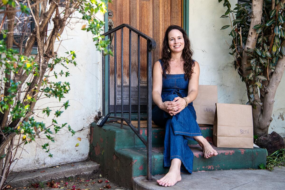 Meredith Klein sits on steps with brown paper grocery bags