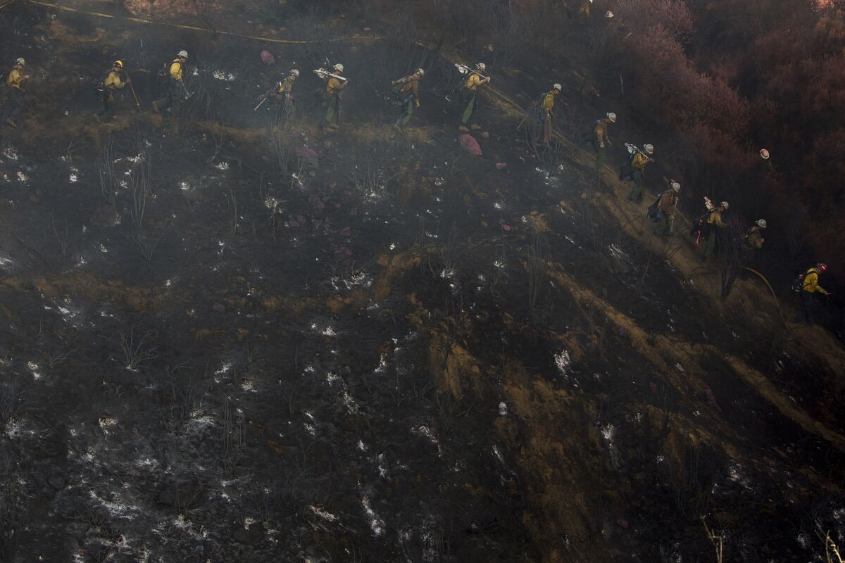 Hand crews line up to work on the remaining hot spots from a brush fire at the Apple Fire in Cherry Valley, Calif., Saturday, Aug. 1, 2020. (AP Photo/Ringo H.W. Chiu)