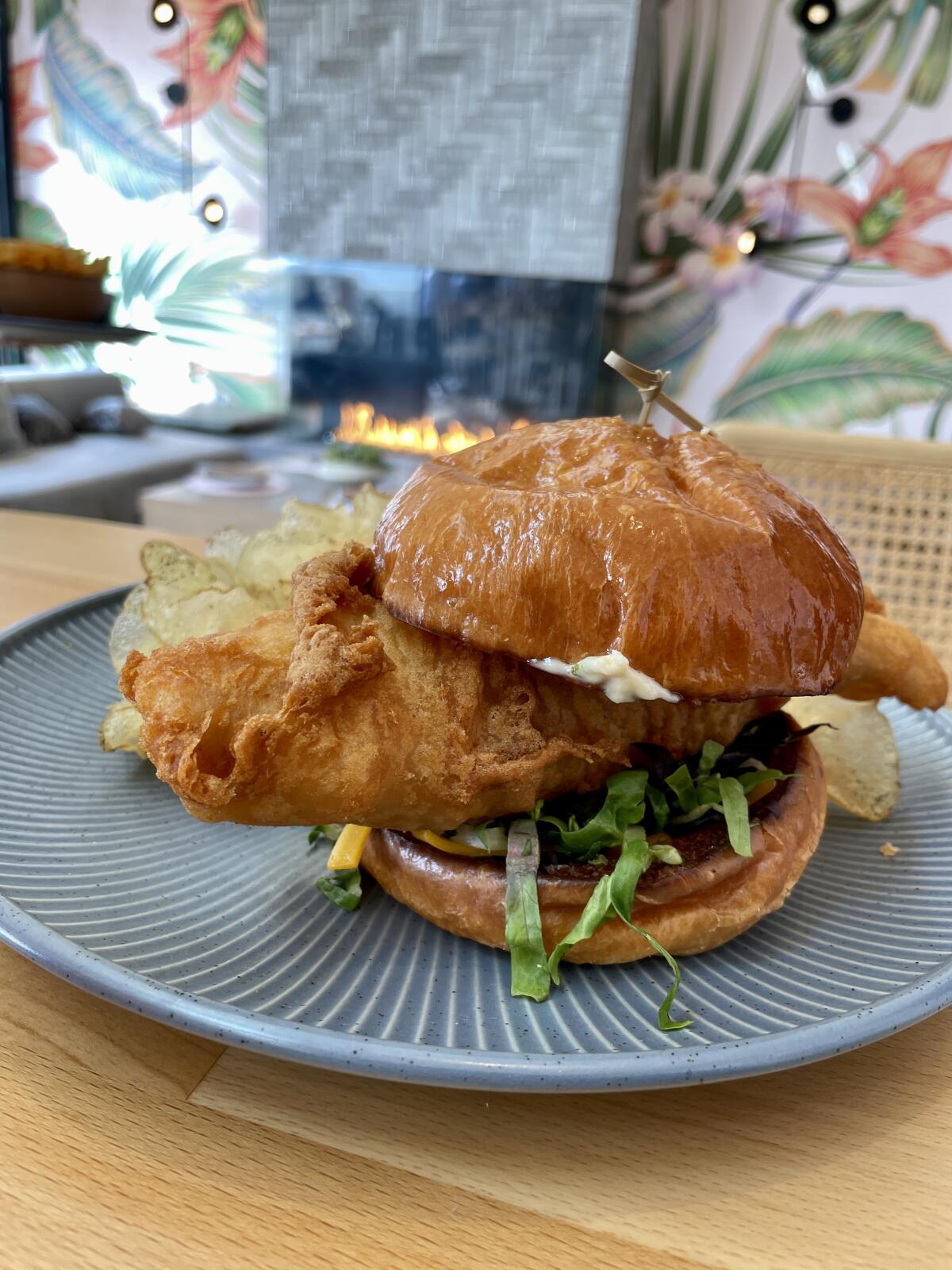 A huge fried-fish sandwich on a plate at a restaurant.