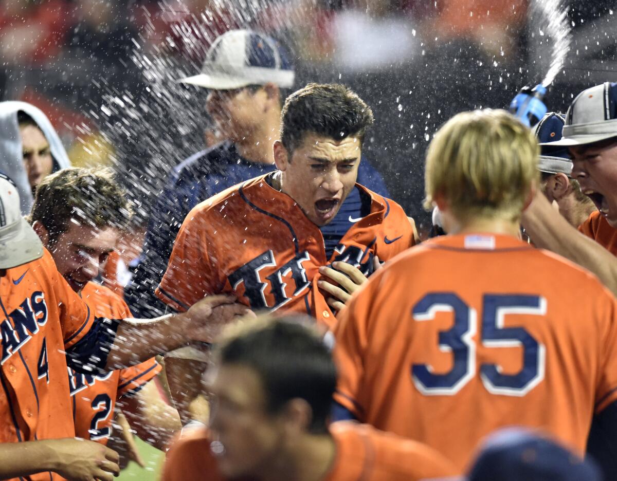 Outfielder David Olmedo-Barrera is congratulated by Cal State Fullerton teammates after hitting a home run against Louisville in the 11th inning of the deciding super regional game on June 8, 2015.