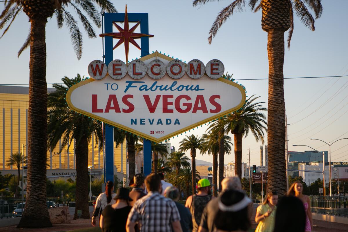 People stand near the "Welcome to Fabulous Las Vegas, Nevada" sign waiting their turn to take a photo in front of it