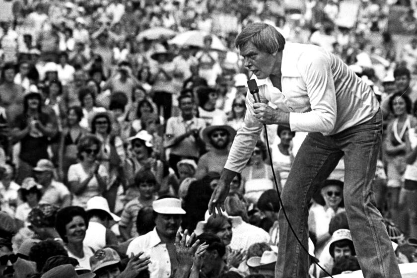 Tom T. Hall leans to the edge of the stage in 1977.