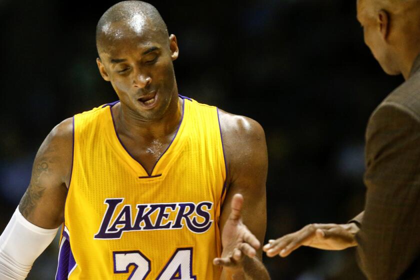 Lakers guard Kobe Bryant gets a hand slap from Coach Byron Scott after leaving the court against the Nuggets in an exhibition game Monday.