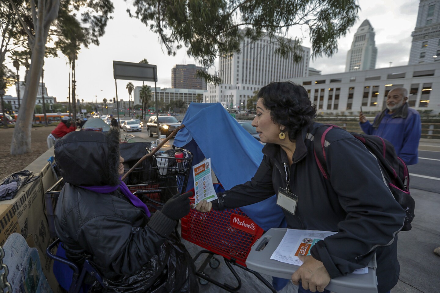 Lisa Pacheco of the Los Angeles Homeless Services Authority, right, gives a leaflet about new rules and restrictions to Alla Gavorkan, 61, who lives in a tent in downtown Los Angeles' El Pueblo historic district.
