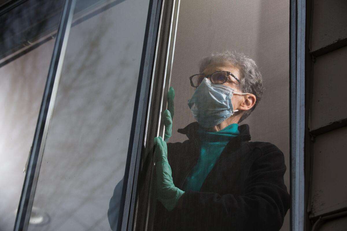 Pat McCauley stares out the window of her home in Kirkland, Wash., while she is quarantined with her husband.  The psychological toll of isolation and loneliness can be as damaging to one's health as smoking, researchers say.