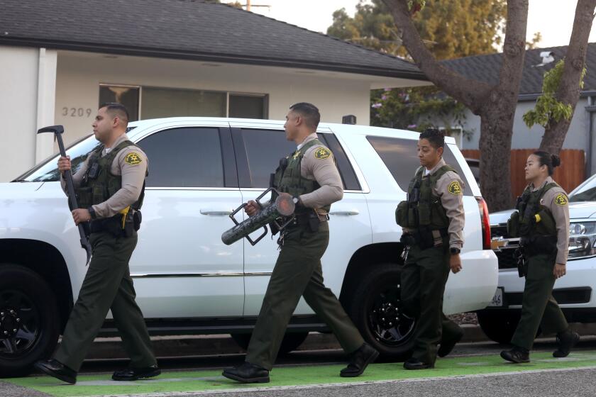 SANTA MONICA, CA - SEPTEMBER 14, 2022 - - Los Angeles County sheriffs approach the home of Los Angeles Supervisor Shelia Kuehl's to serve her with an early morning search warrant in Santa Monica on September 14, 2022. This was part of a criminal investigation into a county contract awarded to a nonprofit organization. Sheriff's investigators also searched Patti Giggans' house, her nonprofit's offices, officers at the L.A. County Hall of Administration and the headquarters of the county's Metropolitan Transportation Authority, which awarded a contract to Giggans' Peace Over Violence." (Genaro Molina / Los Angeles Times)