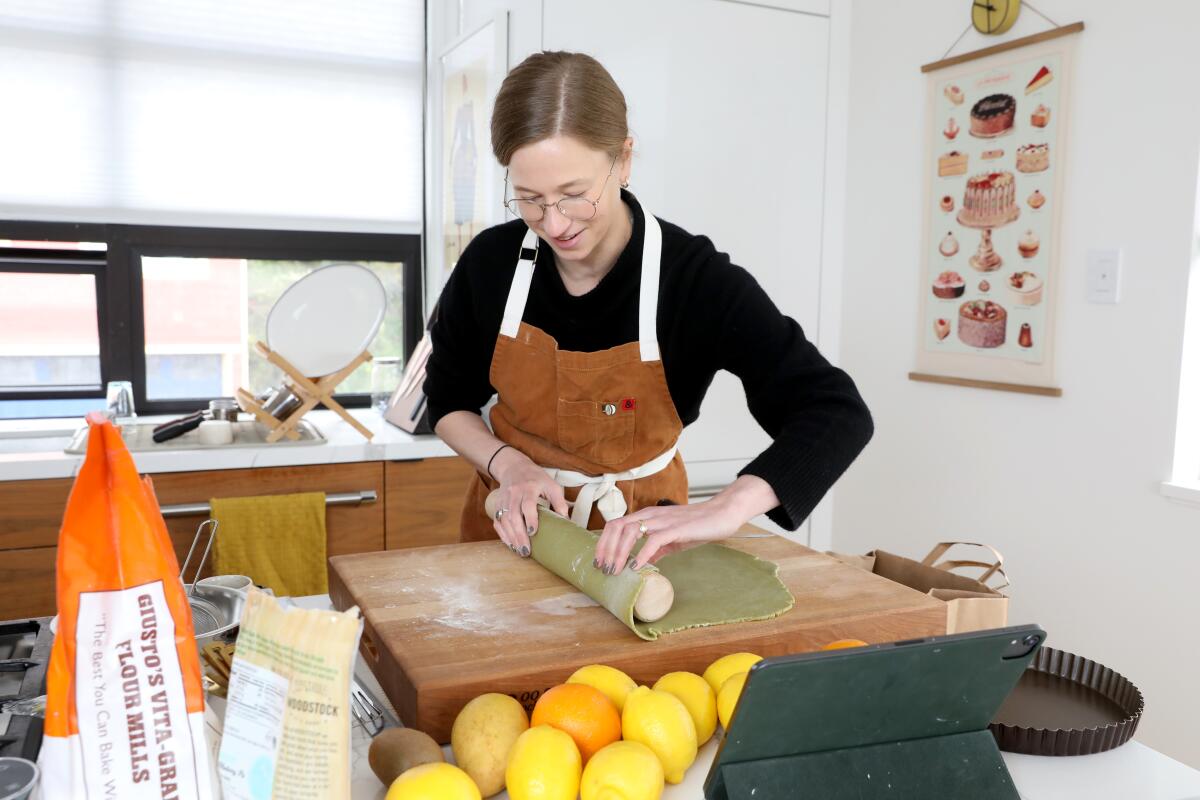 Ariel Friedman rolls tart dough on a cutting board in a kitchen
