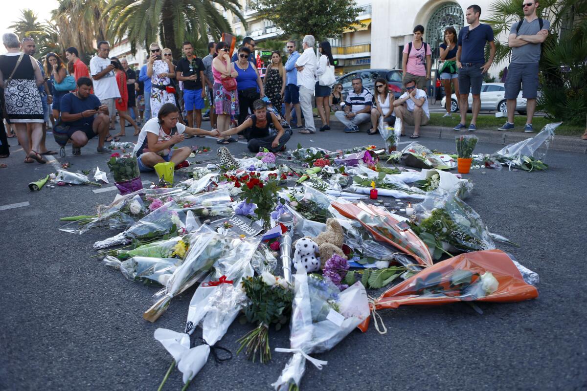 Varias personas rinden homenaje a las víctimas en el lugar donde un camión arrolló a una multitud en la afamada Promenade des Anglais en Niza, en el sur de Francia, el sábado 16 de julio de 2016. El canciller francés Bernard Cazeneuve dice que el chofer del camión que mató a 84 personas en ese lugar se "radicalizó con mucha rapidez". (AP Foto/Francois Mori)