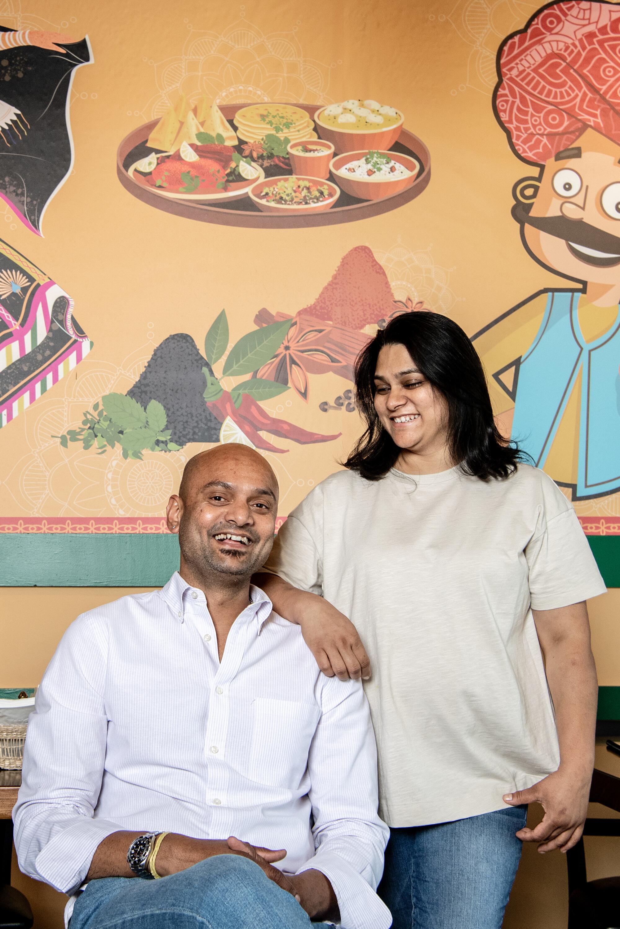 The owners of Bhookhe restaurant, Anshul and Pooja Dwivedi, pose in front of a mural.