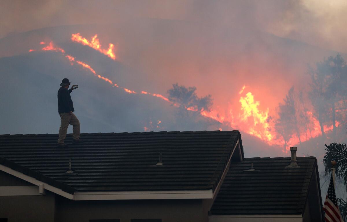 Herman Termeer watches the Blue Ridge fire burn Tuesday inside Chino Hills State Park from the roof of his home.