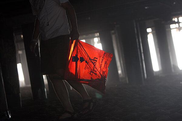 A volunteer carries a bag of trash under the Santa Monica Pier during the 25th annual California Coastal Cleanup Day.