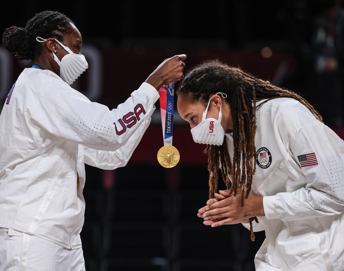 U.S. women's basketball player Tina Charles, left, puts a gold medal around Brittney Griner's neck.