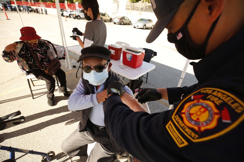 A Los Angeles firefighter administers a COVID-19 vaccine dose at a clinic in Chinatown on Feb. 24. 