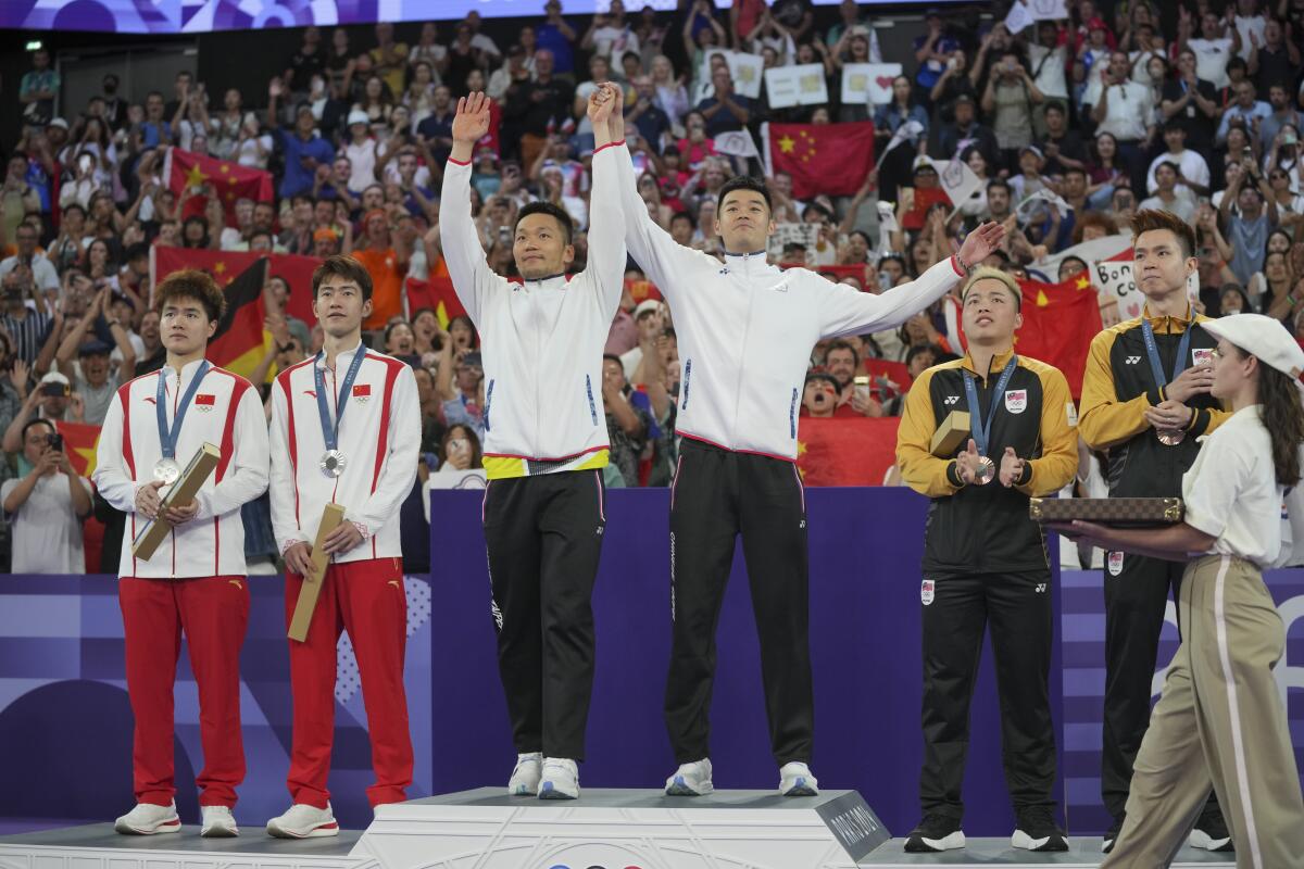 Taiwan’s Lee Yang and Wang Chi-lin stand on the podium after defeating China’s Liang Weikeng and Wang Chang.