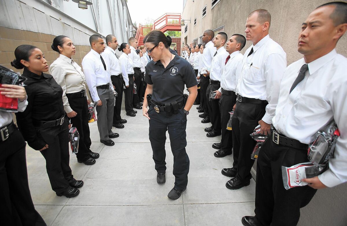 A training instructor at the Los Angeles police academy inspects recruits in their newly issued belts, holsters and duty equipment. The LAPD has required recruits to sign five-year contracts since the mid-1990s, when the department found that some were quitting as early as the day after graduation to work for other departments that did not pay for training.