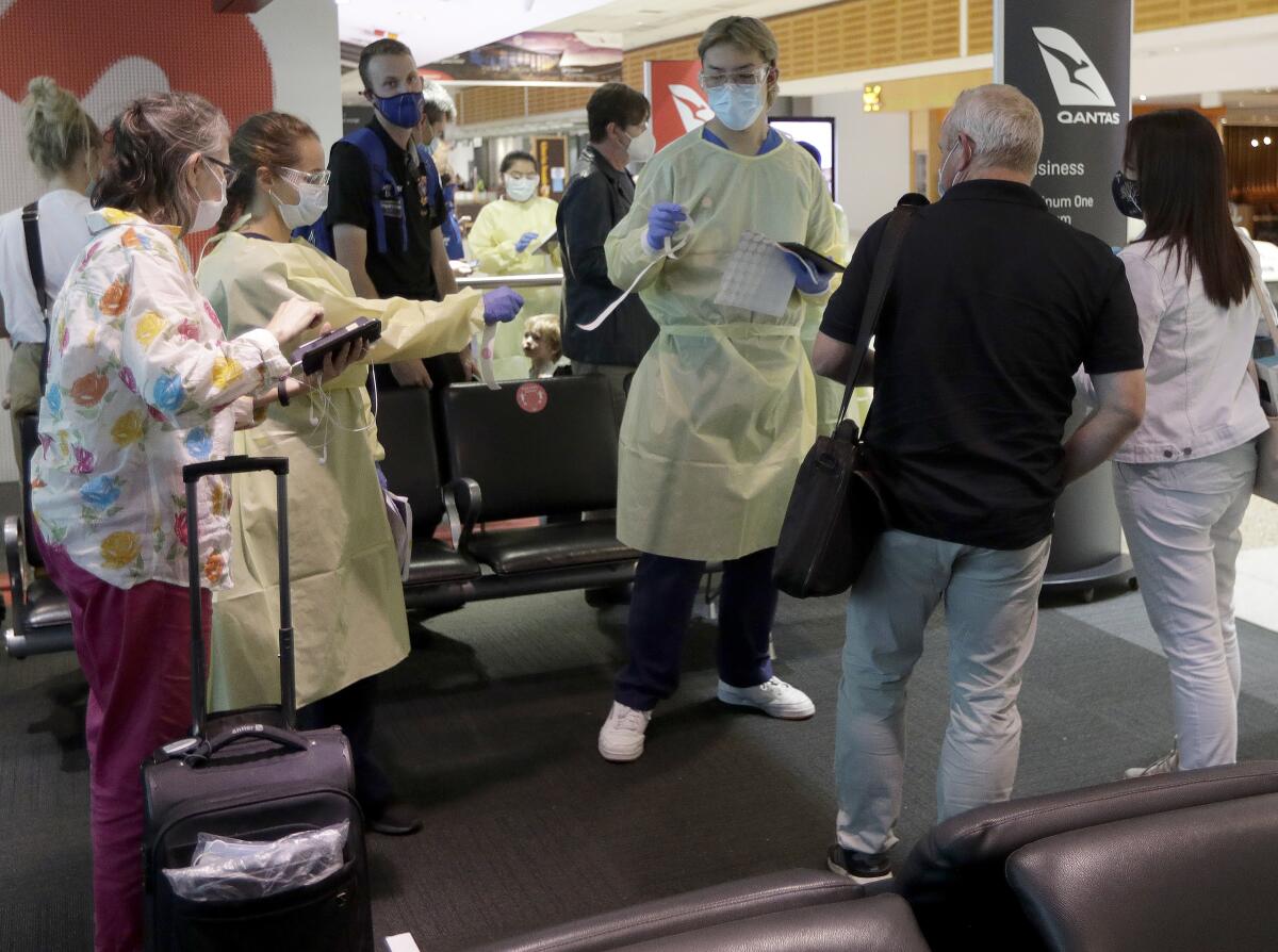 Pasajeros procedentes de Melbourne son revisados por personal de salud en el aeropuerto de Sydney.