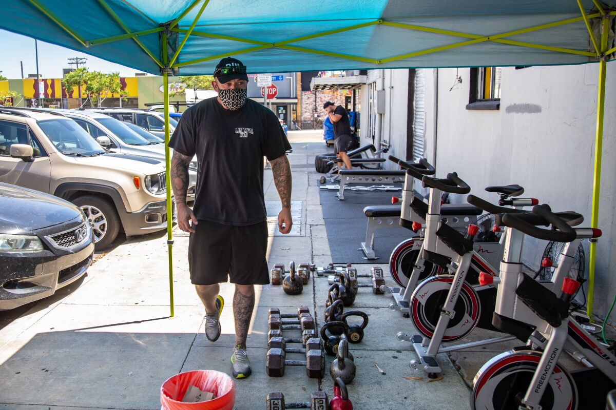 Personal trainer, William Jones, watches over the equipment placed on the sidewalk for gym members.