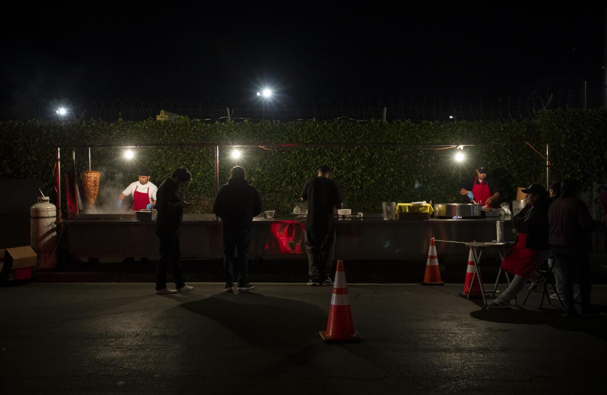 People at a taco stand at night