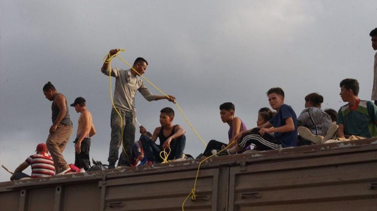 Carlos Onan Galo Perez (with a yellow rope) and members of his family atop a freight train that migrants call La Bestia (the Beast). The train travels through Mexico toward the U.S.