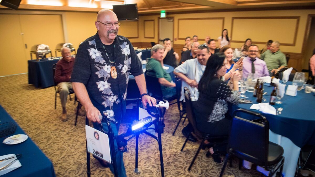Harold Marinelli tests out his retirement gift, a walker with a police light, given to him by partner J.C. Duarte during a retirement party.