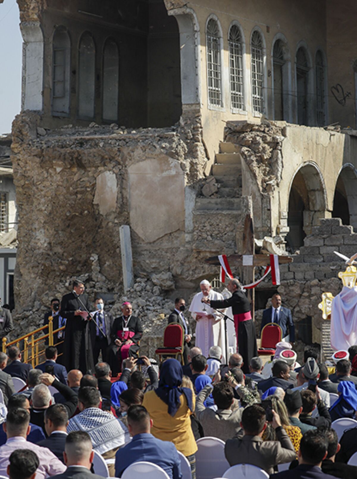 The pope speaks to a group of people in front of the ruins of a building.