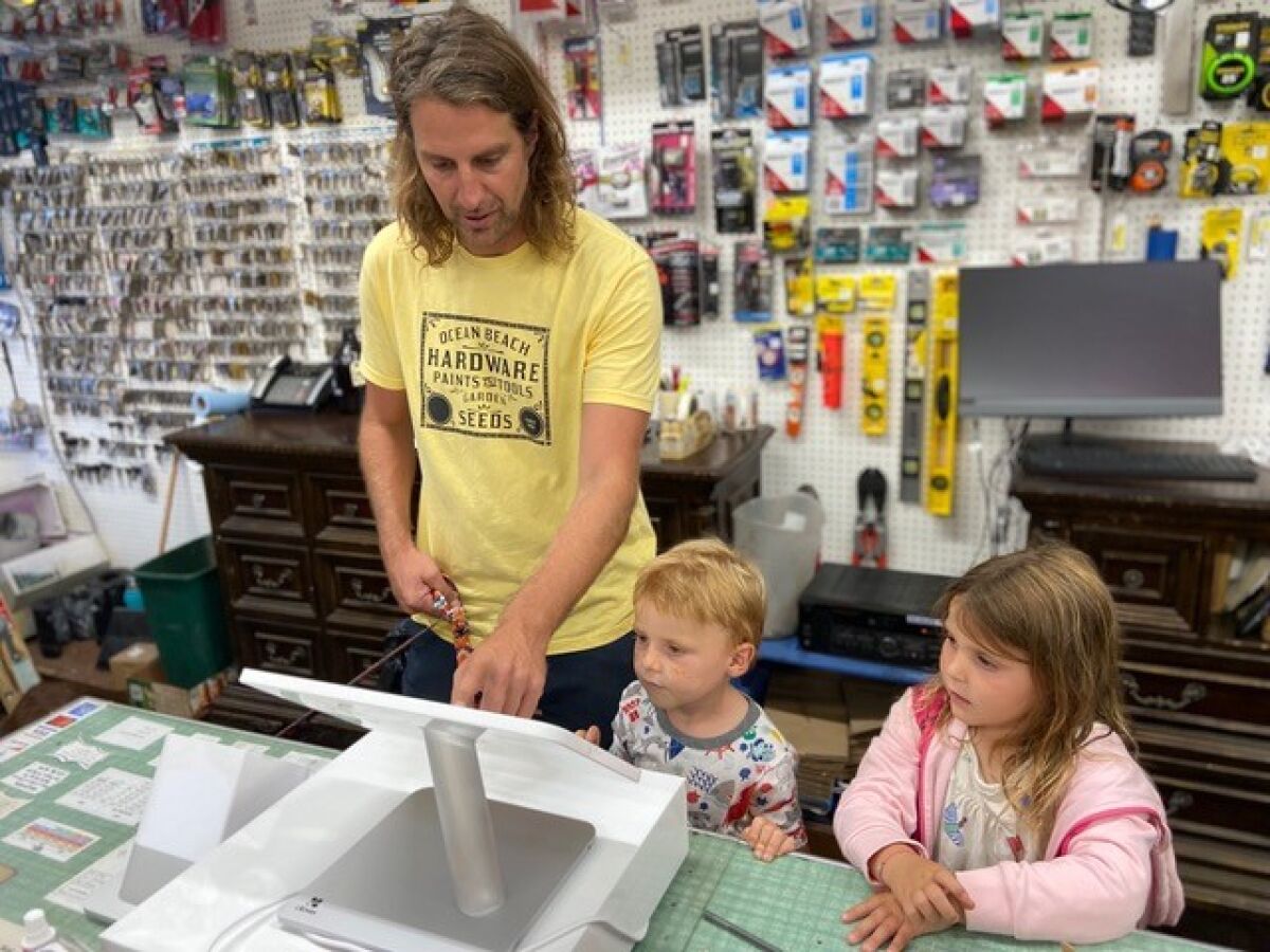 Julian and Ember Kuchman watch their dad, Joe, at work at the family's newly acquired business, OB Hardware.