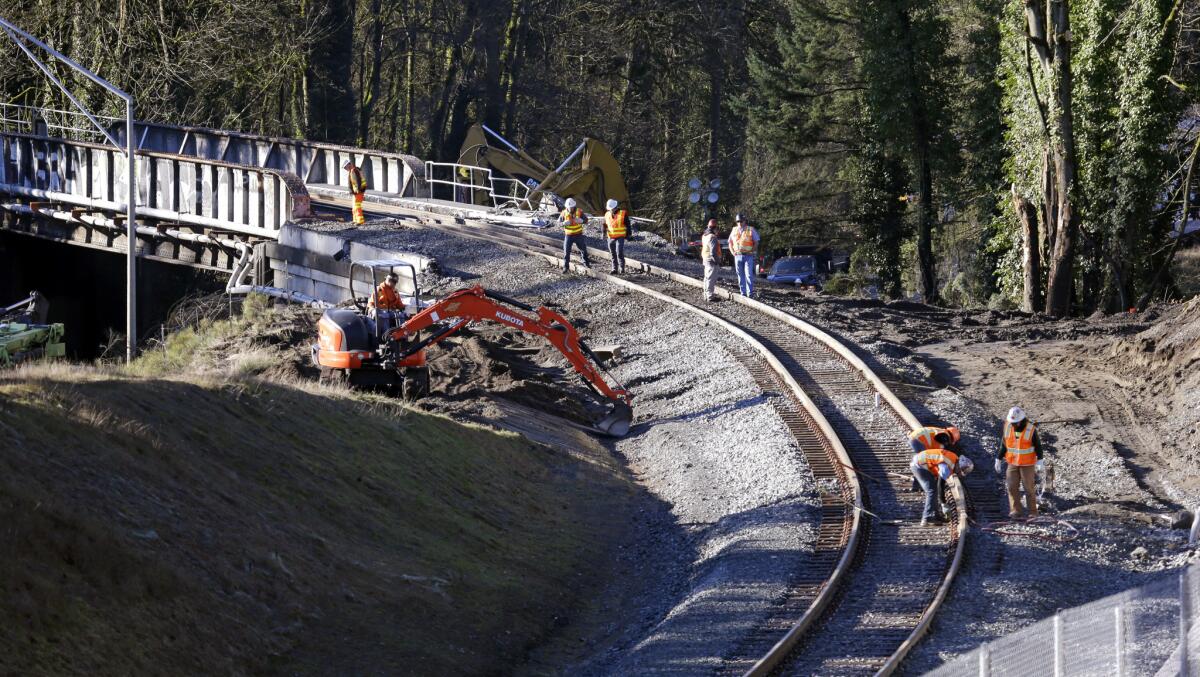 A crew works Wednesday on the curved stretch of track leading to the bridge in Washington state where an Amtrak train derailed two days earlier