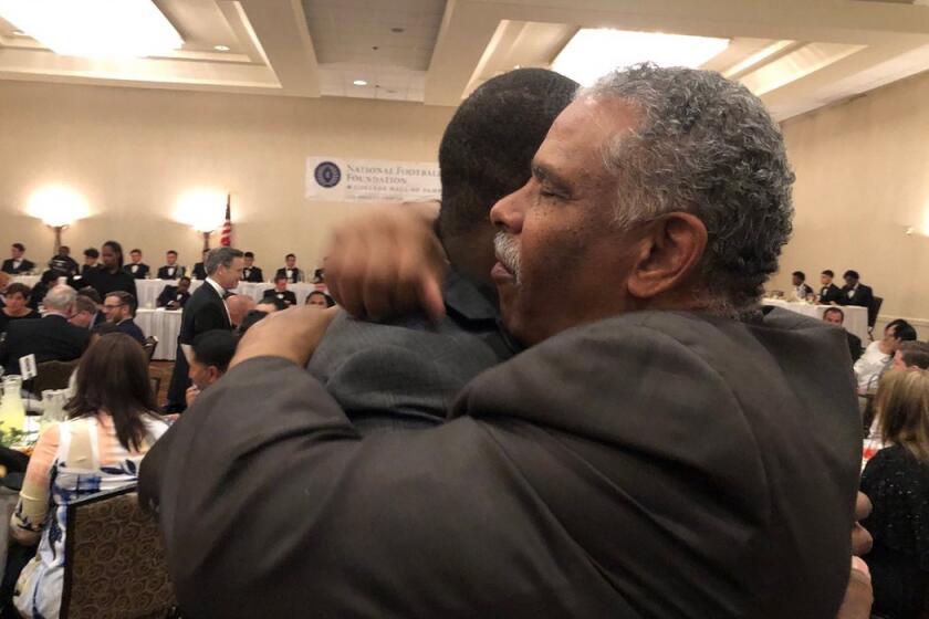 Paul Knox, the football coach at Washington Prep, embraces his former Dorsey player, Johnathan Franklin, at an awards banquet. Knox turns 67 in December and keeps coaching.