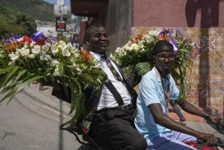 Un hombre transporta coronas de flores en la parte trasera de un mototaxi en Puerto Príncipe, Haití, el domingo 28 de abril de 2024. (Foto AP/Ramón Espinosa)