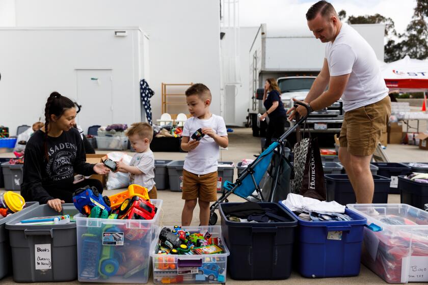 Taylor Knapp, left, and her husband David Knapp, who has been in the Navy for three years, help their children Noah, 1, and Gabriel, 4, pick out toys during a distribution event hosted by nonprofit Support the Enlisted Project (STEP) in Scripps Ranch on Saturday, May 18, 2024. Over 300 San Diego military families were given essential needs including food, clothes, diapers and more.