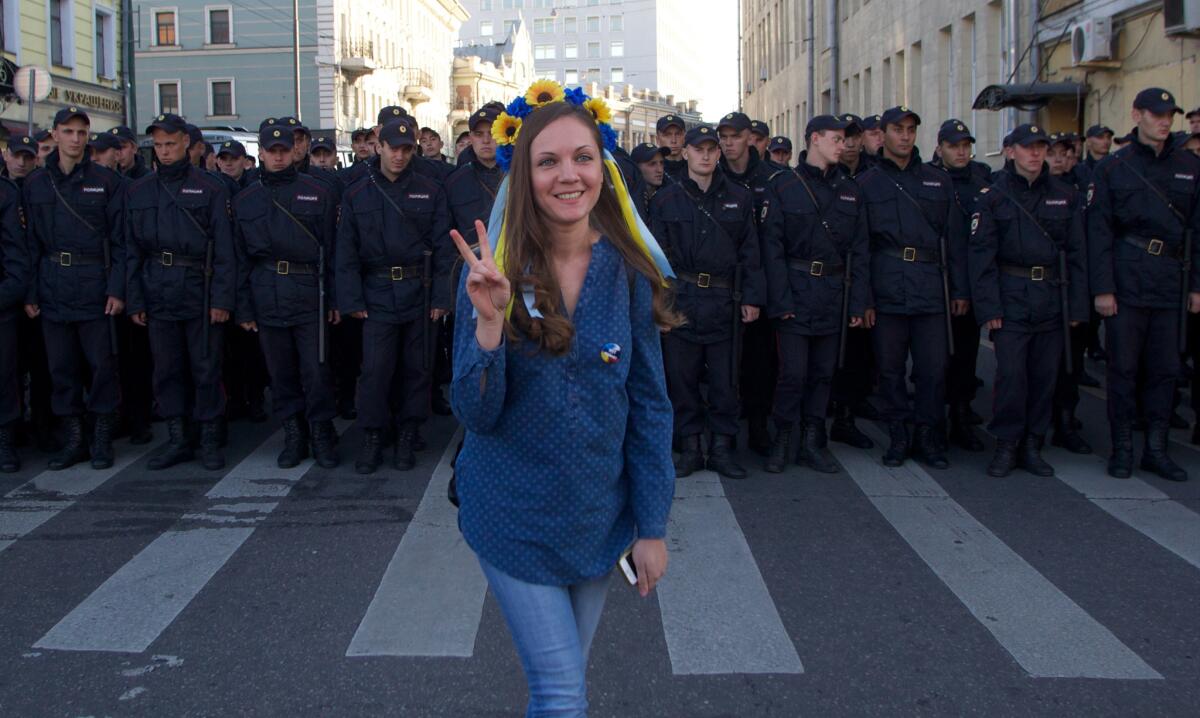 A woman wearing a traditional Ukrainian flower headband poses in front of police officers during an antiwar rally in downtown Moscow on Sunday.