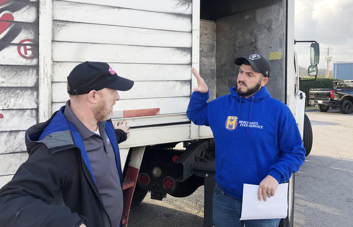 Jerrett Sellers, right, talks to a truck driver in a parking lot.