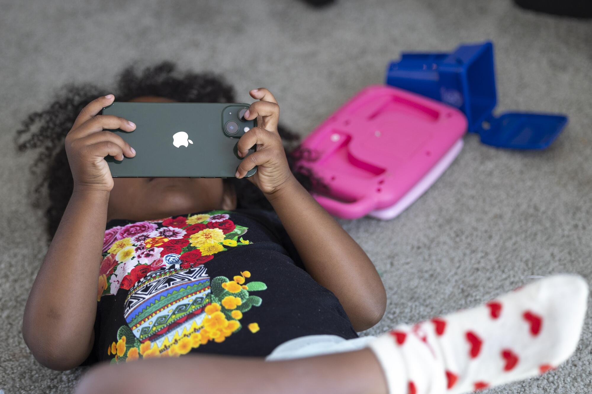 Maya Valree's 3-year old daughter watches an iPhone while her mother works.