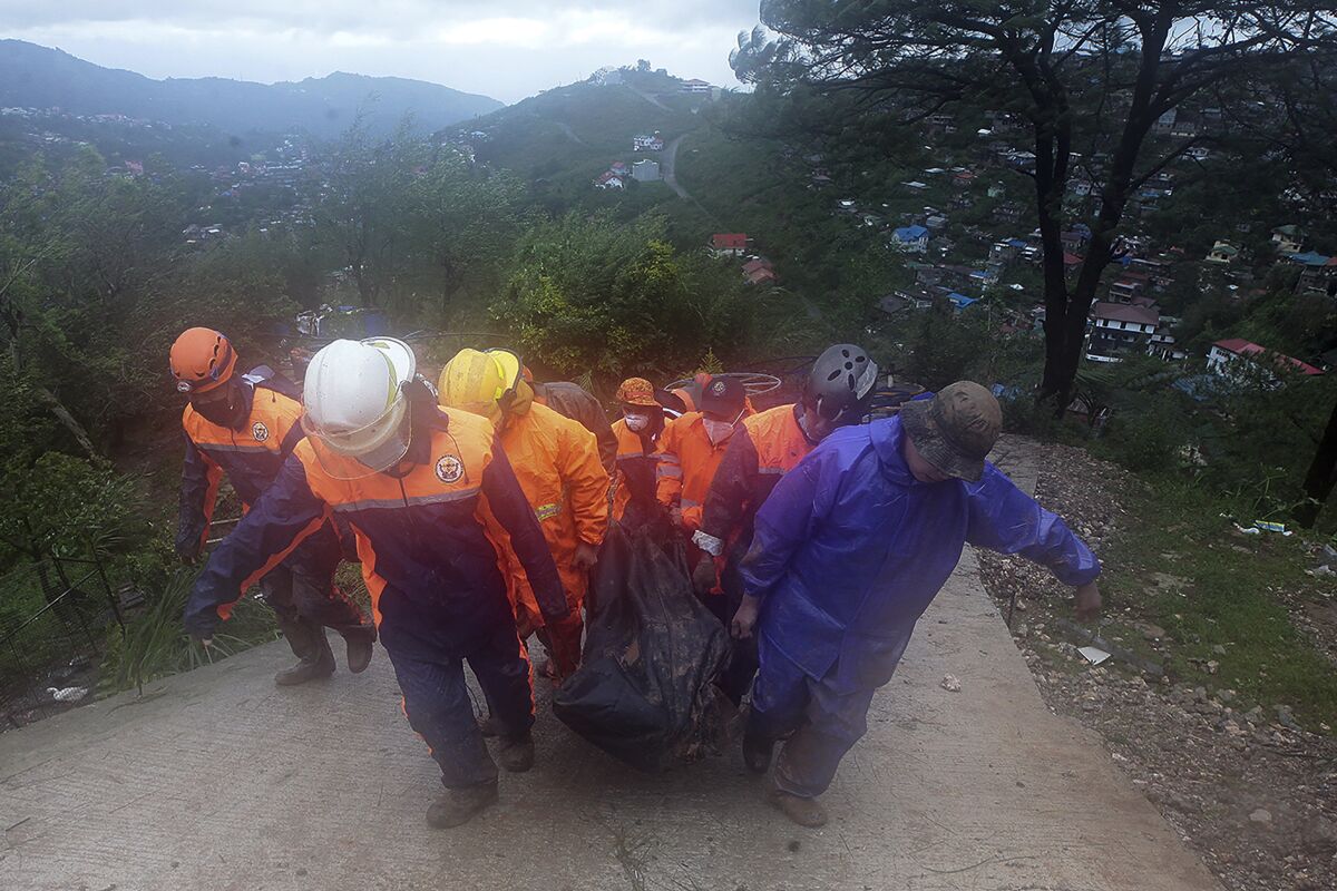 Rescuers carry the body of a victim caught in a landslide caused by Tropical Storm Kompasu in Baguio city, northern Philippines on Tuesday Oct. 12, 2021. A number of people have been killed and others were reported missing in landslides and flash flood set off by a storm that barreled through the tip of the northern Philippines overnight then blew away Tuesday, officials said. (AP Photo)