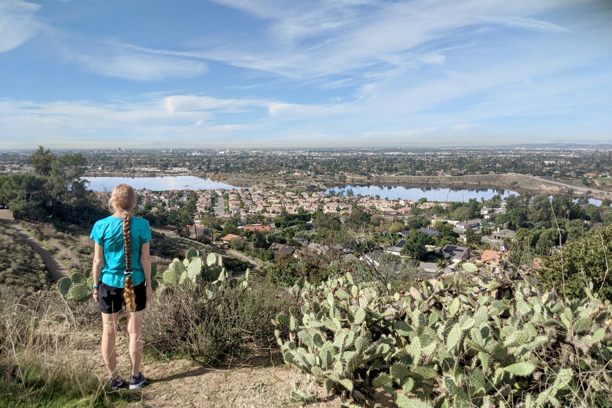 A hiker stops and looks out at the view from the El Modena hike