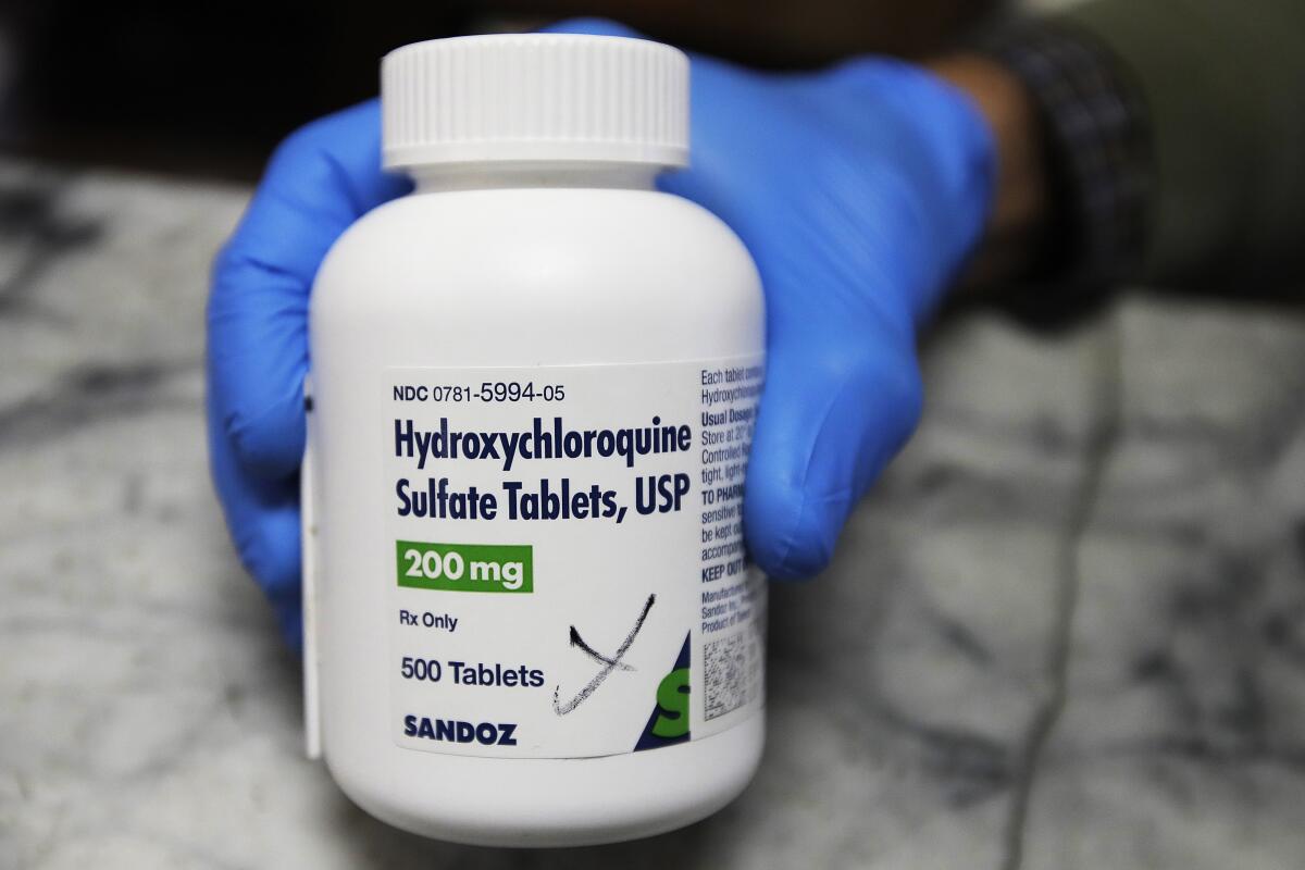 A pharmacist holds a bottle of the drug hydroxychloroquine in Oakland. 