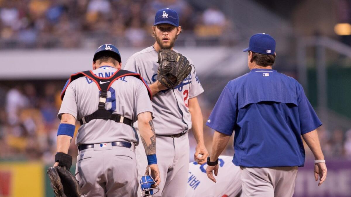 The Dodgers are without the injured Clayton Kershaw, center, getting a visit from catcher Yasmani Grandal and pitching coach Rick Honeycutt in a recent game.