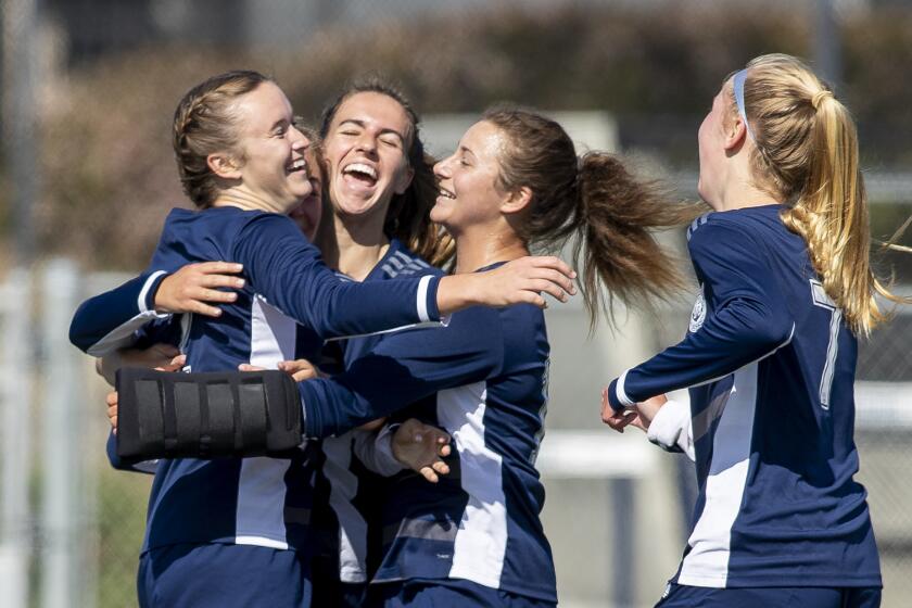 Newport Harbor's teamates hug Laine Briggs, left, after she scored a goal against Corona del Mar during the annual Battle of the Bay match at Newport Harbor High School on Tuesday, April 6.