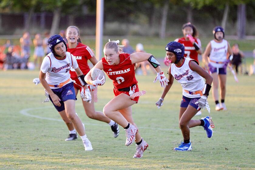 Orange Lutheran flag football player Kaylie Whitsell runs with the ball between two Roosevelt players