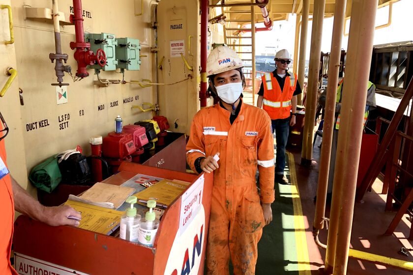 LONG BEACH, CALIF., OCT. 14, 2021: Twenty-four year-old Indonesian seafarer Abrorizki Geraldy Aulia, in the foreground, served as a crew member of the Southern Korean flagged bulk cargo ship Pan Amber for 15 months without a break as the pandemic raged and helped slow the global supply chain of goods movement to a crawl. (Ronald D. White / Los Angeles Times)