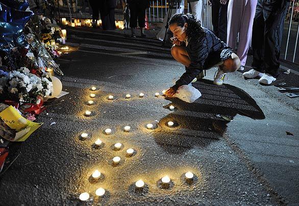Kena Patterson, of Los Angeles, writes out "MJ" with lighted candles at a makeshift memorial outside the Encino family home of late pop star Michael Jackson.