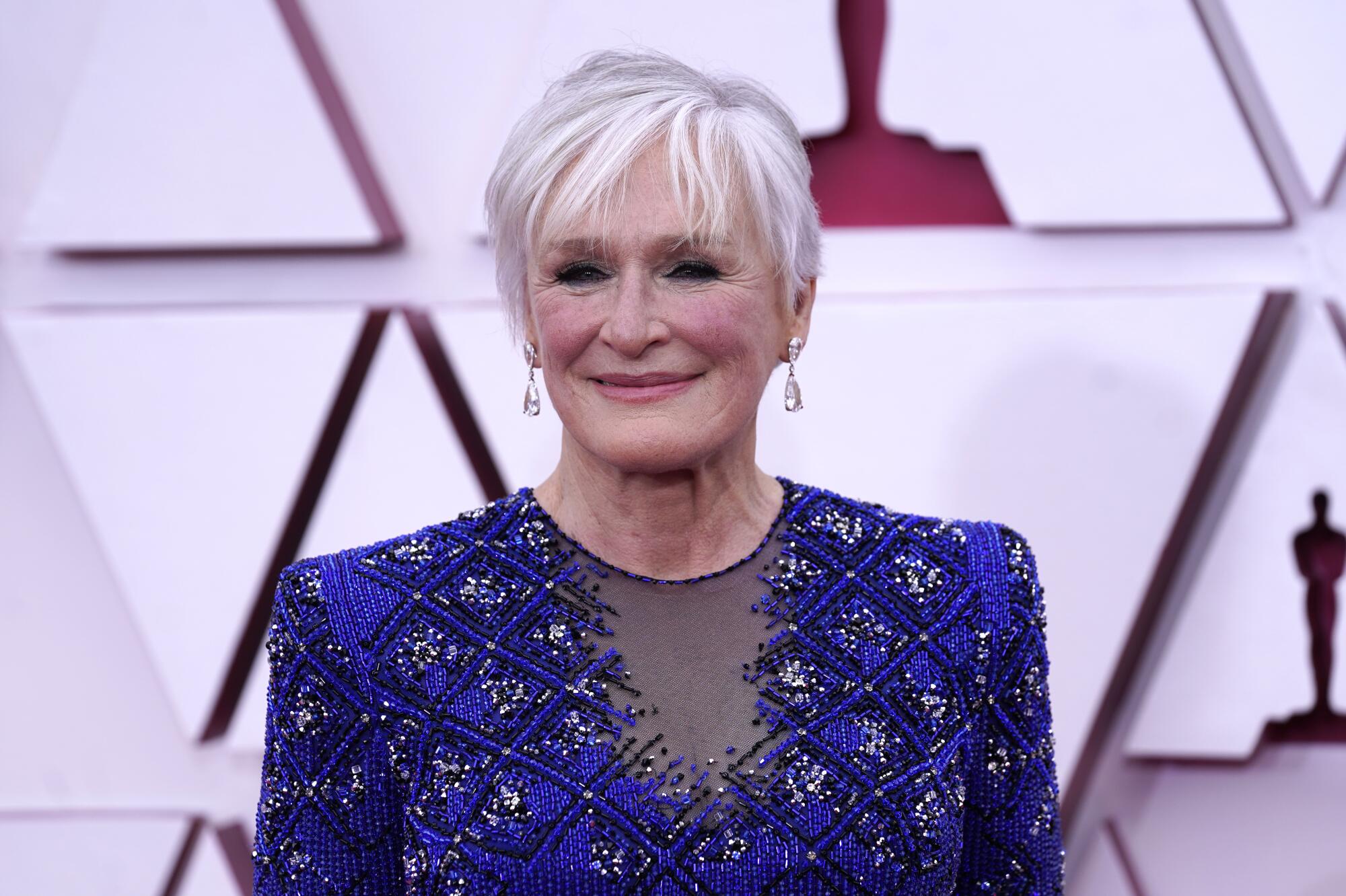Wearing a blue patterned tunic with silk pants and evening gloves, Glenn Close arrives at the Oscars.