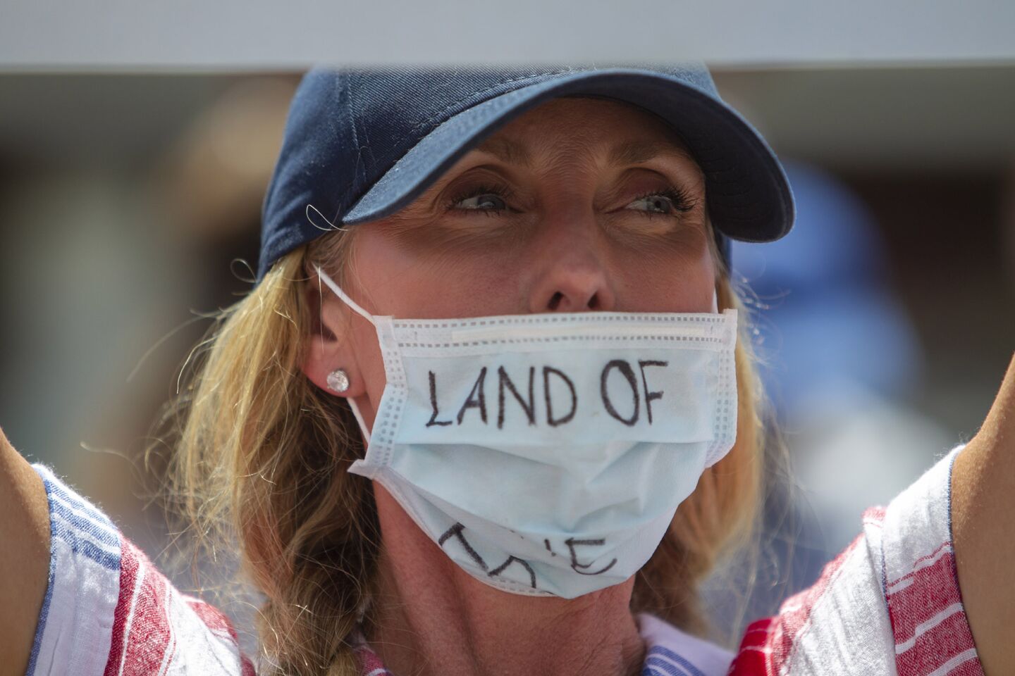 A protester who refused to give her name has a message on a mask during a protest in Huntington Beach.