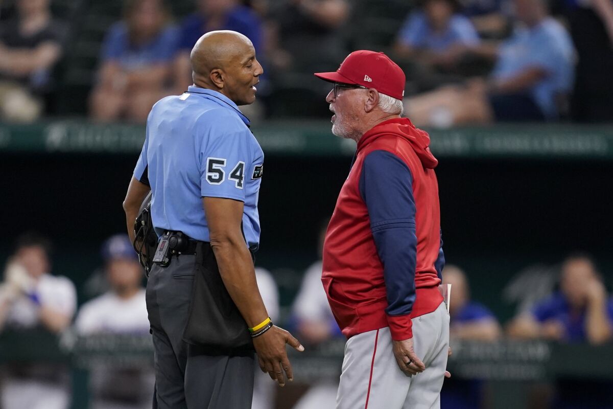 Umpire CB Bucknor talks with Los Angeles Angels manager Joe Maddon, right, after ejecting Maddon during the ninth inning of the team's baseball game against the Texas Rangers, Wednesday, May 18, 2022, in Arlington, Texas. (AP Photo/Tony Gutierrez)