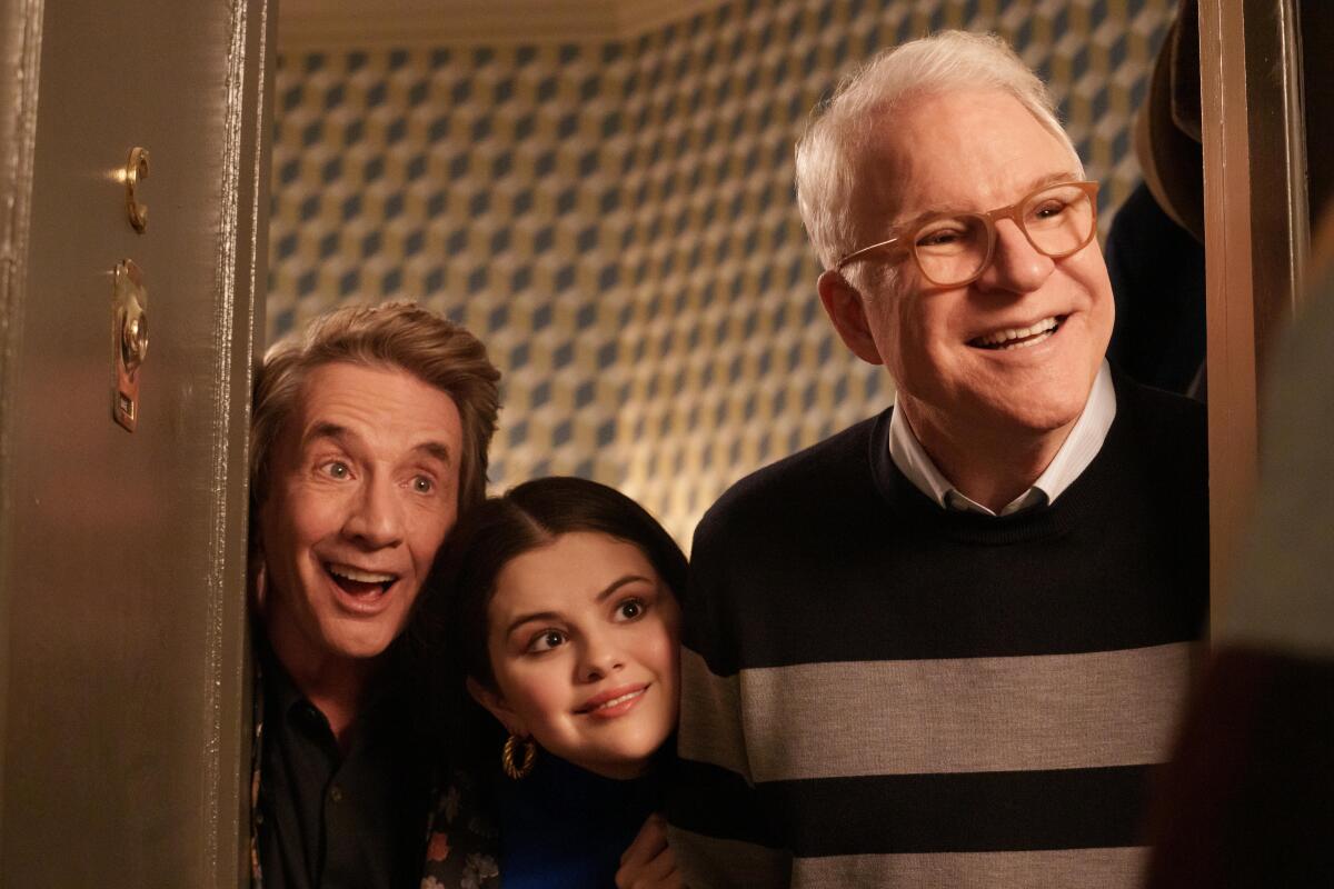 Two older men and a young woman peer out of an elevator in a scene from "Only Murders in the Building."