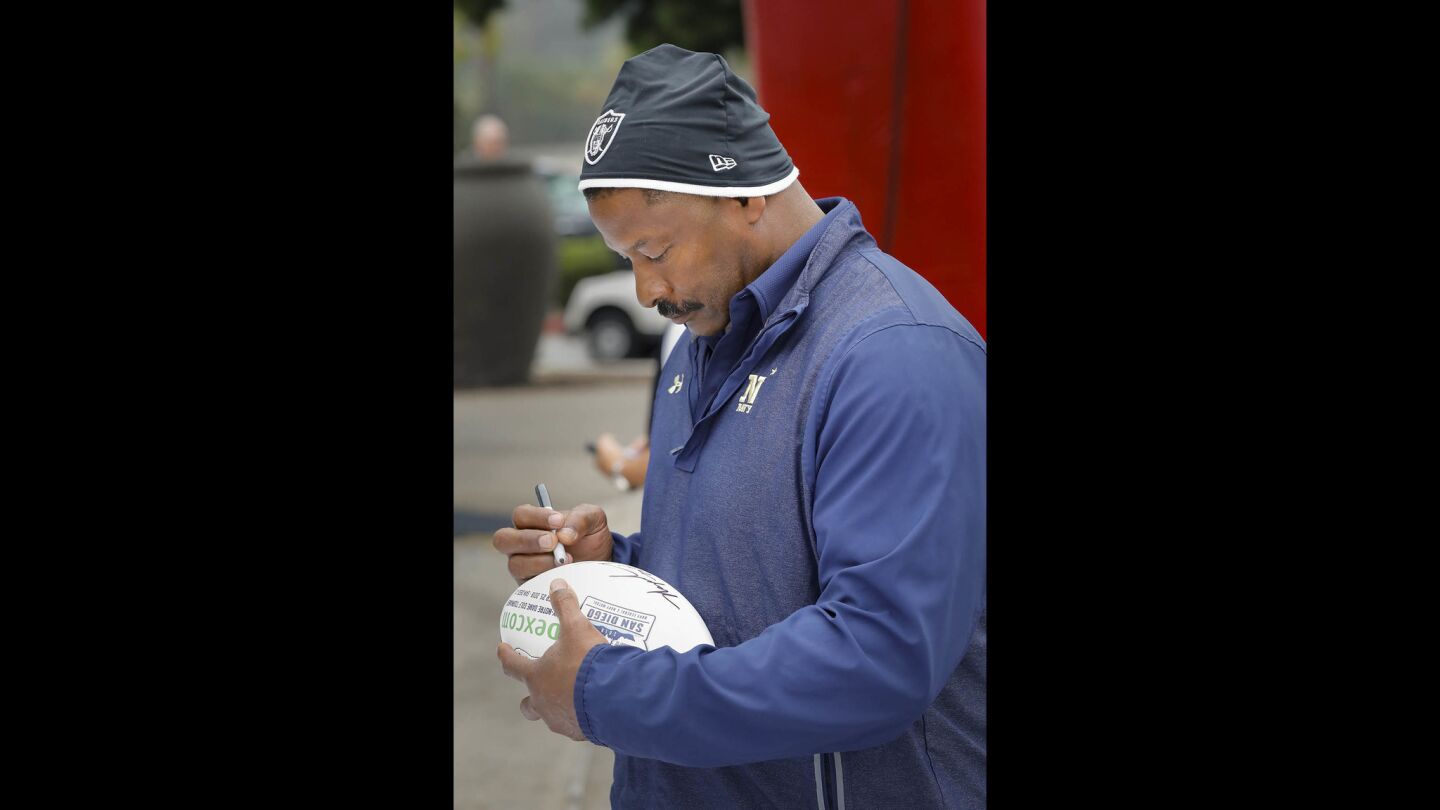 Napoleon McCallum who played football for the U.S. Naval Academy and Oakland Raiders, signs autographs on footballs during the Navy-Notre Dame Golf Tournament at the Riverwalk Golf Club in Mission Valley in advance of the football game between the two schools to be held at SDCCU Stadium, Saturday.